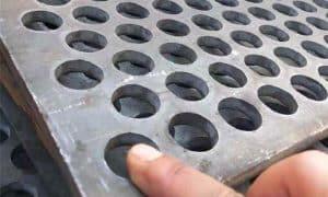 Close-up view of perforated holes on high manganese steel sheet