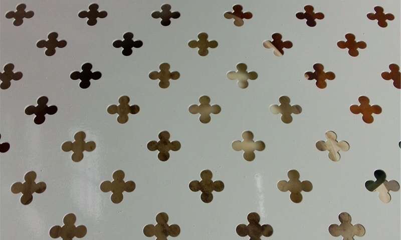 Lembaran logam berlubang silang yang menunjukkan pola lubang khas yang dirancang untuk penggunaan industri