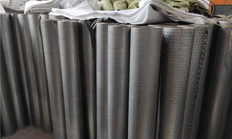 Gulungan lembaran logam berlubang bundar di gudang