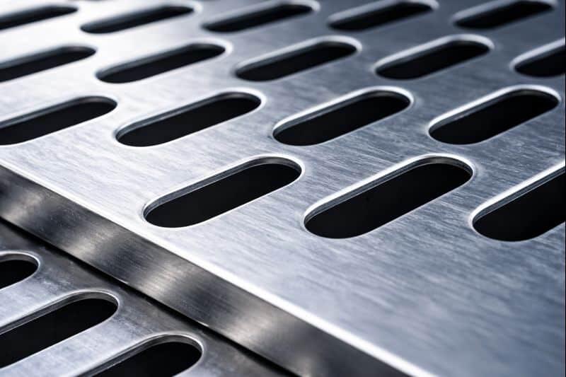 Close-up macro photo of elongated perforated metal sheet showing long-round holes and metal thickness